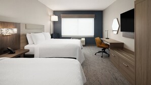 Ein Hotelzimmer mit zwei Betten, einem Schreibtisch mit Stuhl, einem Fernseher, einem großen Fenster und einem Kleiderschrank.