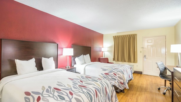 A hotel room with three beds, a desk, a chair, and a door. - Red Roof Inn Clarksville (Clarksville)