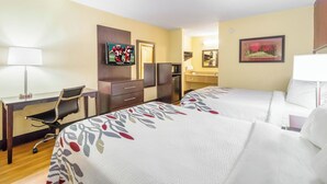A hotel room with two beds, a desk, a chair, a TV, a coffee machine, and a bathroom with a mirror and towel rack. - Red Roof Inn Clarksville (Clarksville)