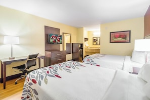 A hotel room with two beds, a desk, a chair, a TV, a coffee machine, and a bathroom with a mirror and towel rack. - Red Roof Inn Clarksville (Clarksville)