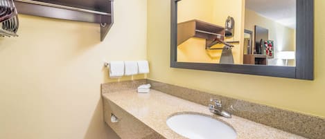 A bathroom with a granite countertop, a white sink, a mirror, and a towel rack.