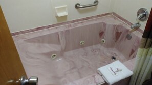A bathroom with a marble bathtub, a handrail, a towel, and a soap dish. - Red Roof Inn Clarksville (Clarksville)