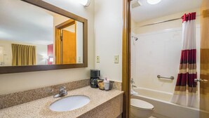 A bathroom with a granite countertop, a sink, a mirror, a coffee maker, and a shower with a curtain. - Red Roof Inn Clarksville (Clarksville)