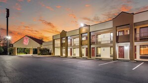 A motel with a red roof sign, multiple floors, and a parking lot. - Red Roof Inn Clarksville (Clarksville)
