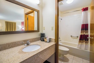 Baño con lavamanos, espejo, cafetera y ducha.