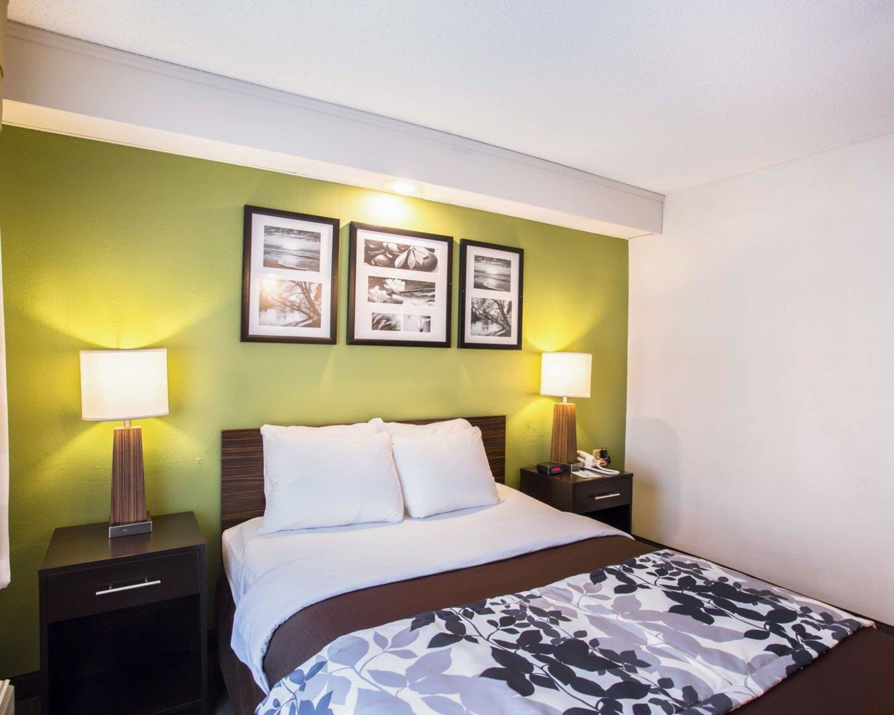A hotel room with a bed, two bedside tables, a nightstand, and a wall with three framed pictures.