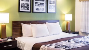 A hotel room with a bed, two bedside lamps, a nightstand, and three framed pictures on the wall. - Sleep Inn Nashville Downtown Opryland Area (Nashville)