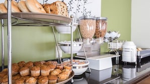 A buffet setup with various baked goods, including muffins and bread, and containers of cereal and granola. - Sleep Inn Nashville Downtown Opryland Area (Nashville)