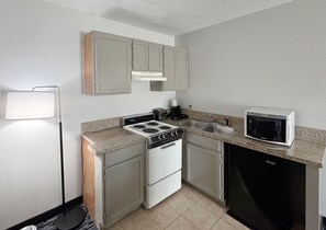 A compact kitchen with a stove, microwave, sink, and cabinets. - Baymont by Wyndham Sevierville Pigeon Forge (Sevierville)
