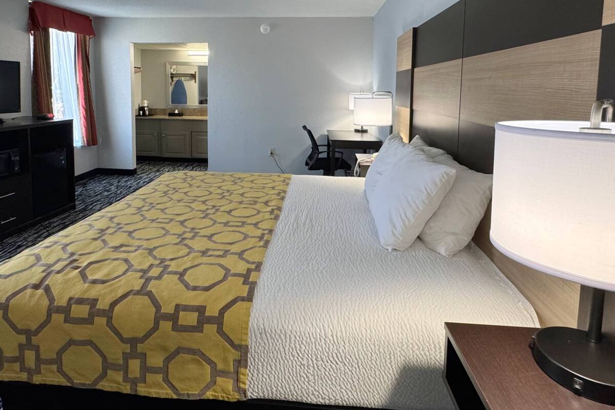 Een hotelkamer met een bed, een bureau, een stoel, een televisie en een badkamer op de achtergrond.