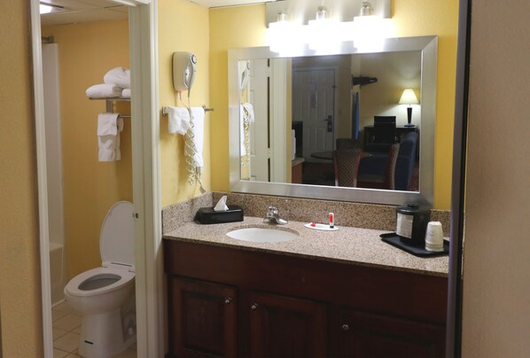 Un baño con lavamanos, espejo, toallero y retrete.