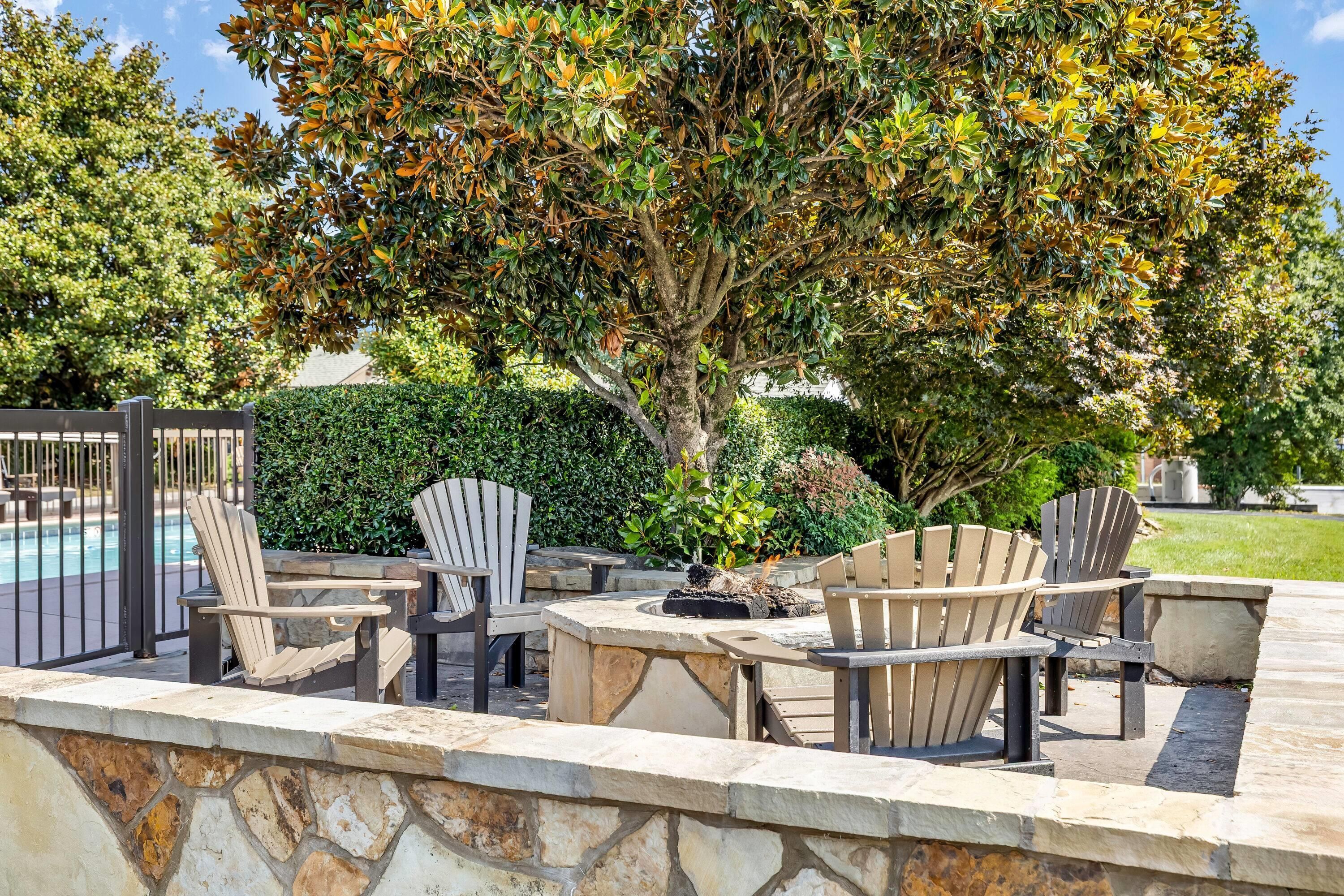 An outdoor seating area with Adirondack chairs and a stone wall.