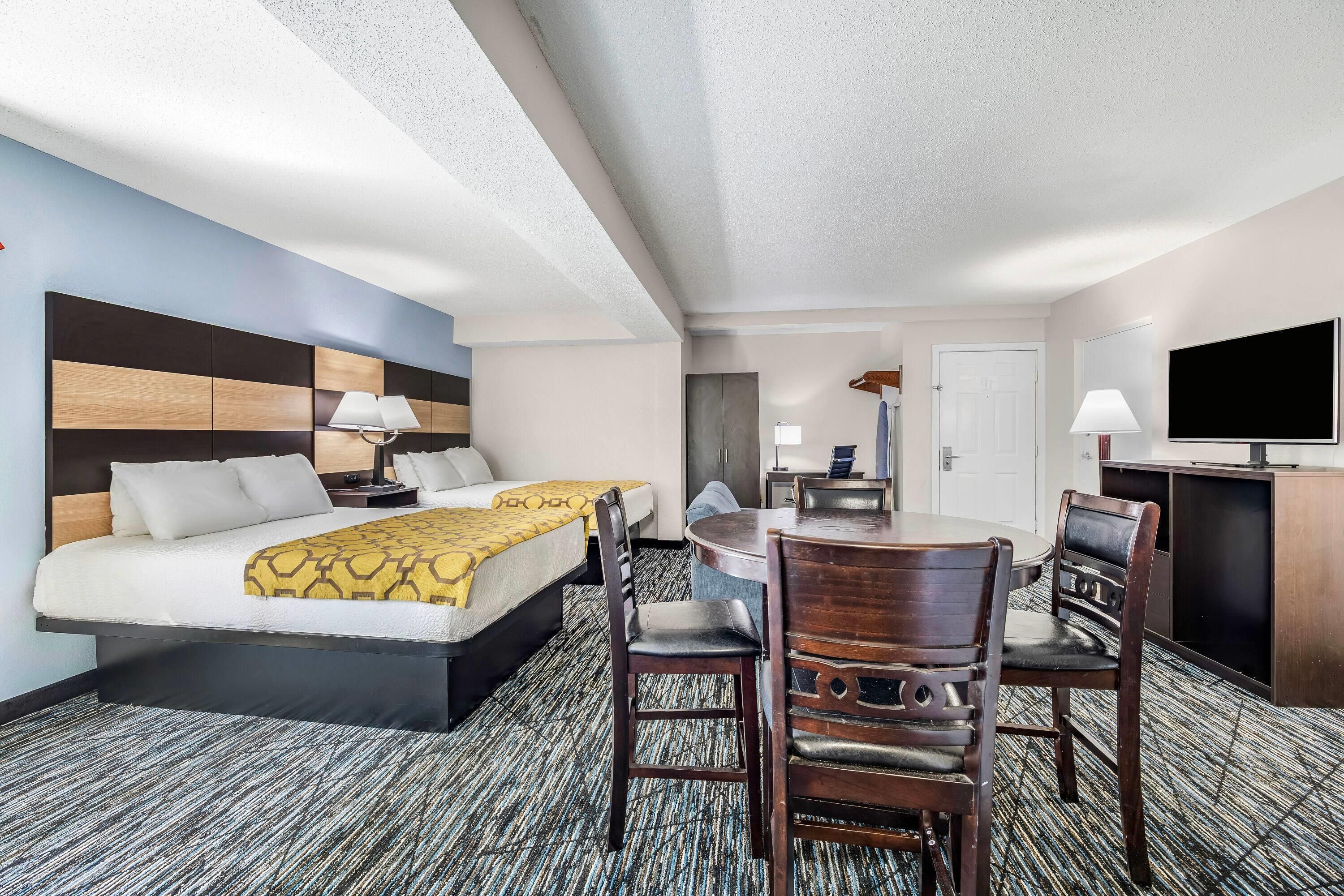 Una habitación de hotel con cama, mesitas de noche, escritorio, silla, televisor y puerta.