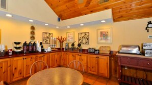 A kitchen with wooden cabinets, a round table, and various kitchen appliances.