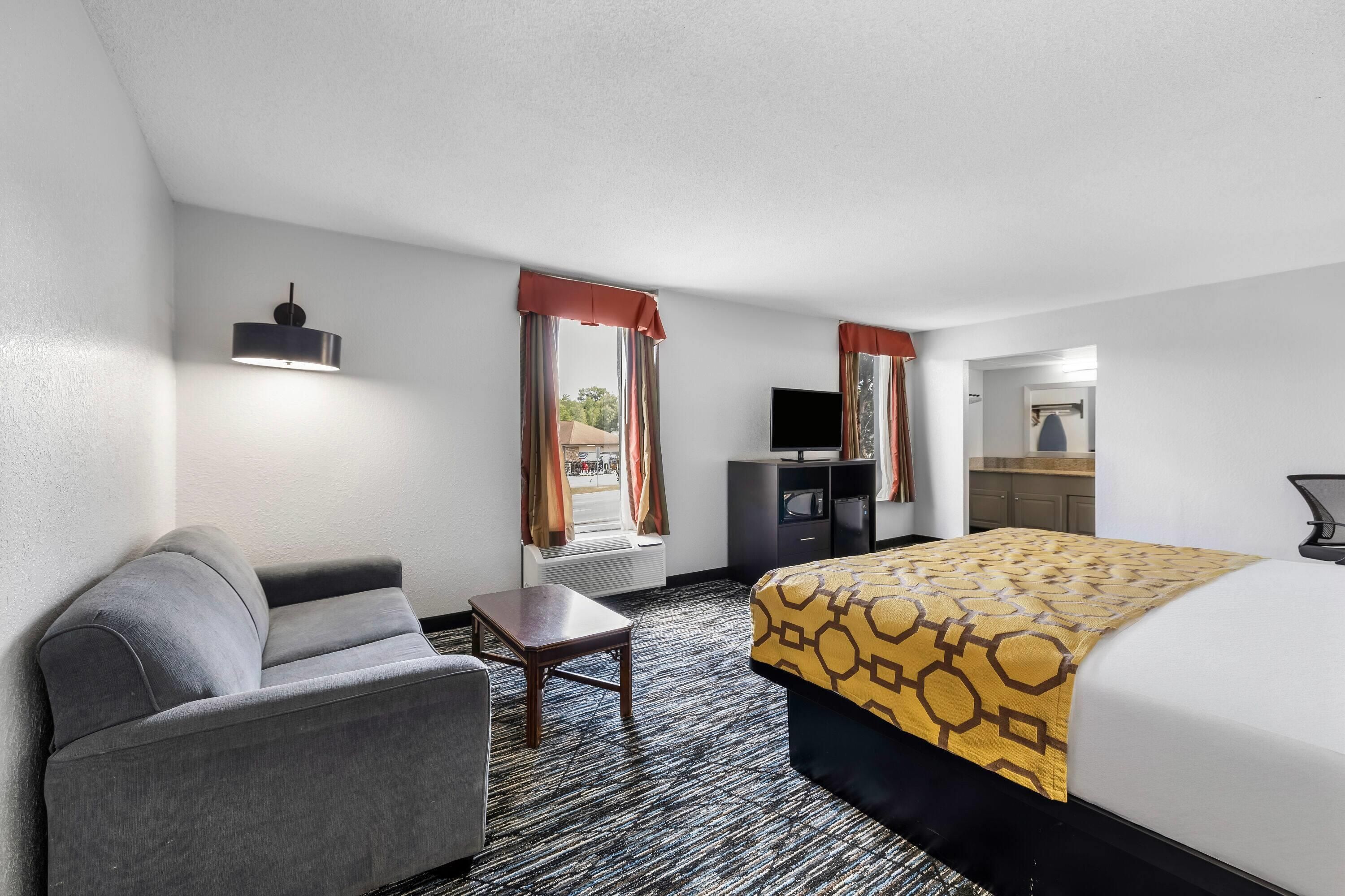 A hotel room with a bed, a desk, a chair, a TV, and a wardrobe.