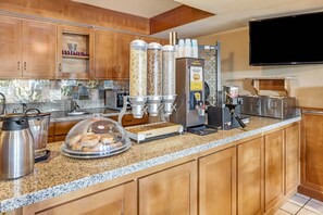 Een keuken met een wafelijzer, een koffieapparaat en een waterdispenser.