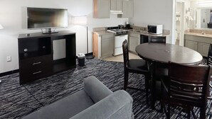 Une chambre d’hôtel compacte comprenant un coin cuisine, un espace repas, un canapé et une télévision.