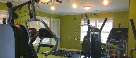 A gym with exercise equipment, a treadmill, and a mirrored wall.