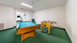 A room with a pool table, a foosball table, and a chair. - Travelodge by Wyndham Decatur TX I-287 (Decatur)