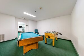 A room with a pool table, a foosball table, and a chair. - Travelodge by Wyndham Decatur TX (Decatur)