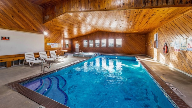 Piscina interna com paredes e teto de madeira, azulejos claros e aviso de proibição de fumar.
