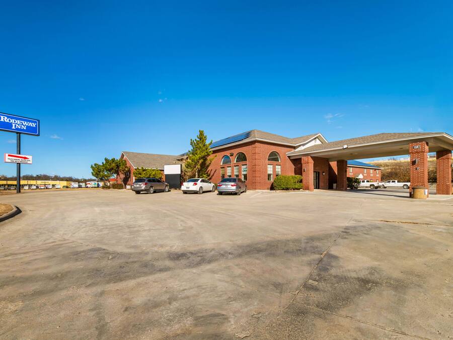 A motel with a clear sign, a parking lot, and a gas station.