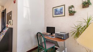 A small office space with a desk, computer, printer, and chair. There are plants on the wall and a fire alarm on the left. - Travelodge by Wyndham Decatur TX I-287 (Decatur)