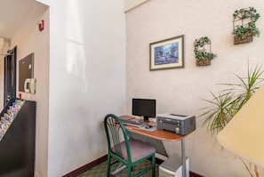 A small office space with a desk, computer, printer, and chair. There are plants on the wall and a fire alarm on the left. - Travelodge by Wyndham Decatur TX (Decatur)