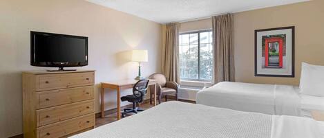 A hotel room with two beds, a desk with a chair, a television, and a window with curtains.