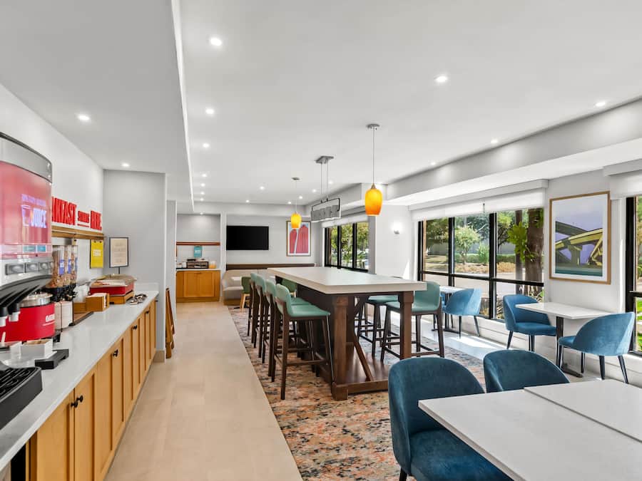 A modern breakfast area with a coffee machine, seating, and a view of the outdoors.
