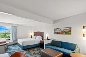 A hotel room with a bed, a sofa, a desk, and a window with a view of greenery. - Hampton Inn Houston-Willowbrook Mall (Houston)