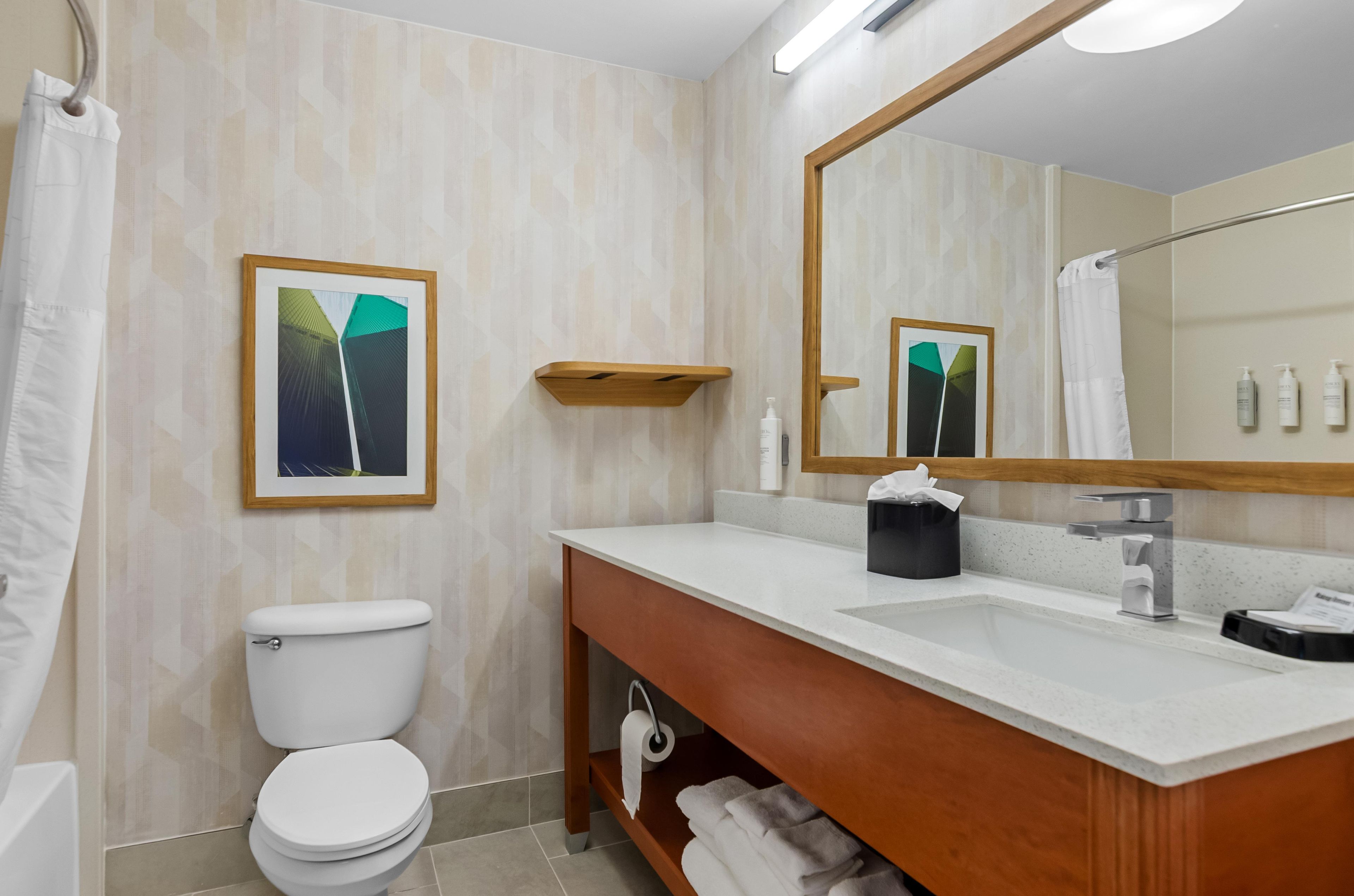 Un baño con inodoro, lavamanos, espejo y toallero.