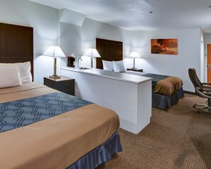 Habitació d'hotel amb un llit gran, un altre més petit, un escriptori i una cadira. Hi ha dues làmpades a l'escriptori i un quadre a la paret.