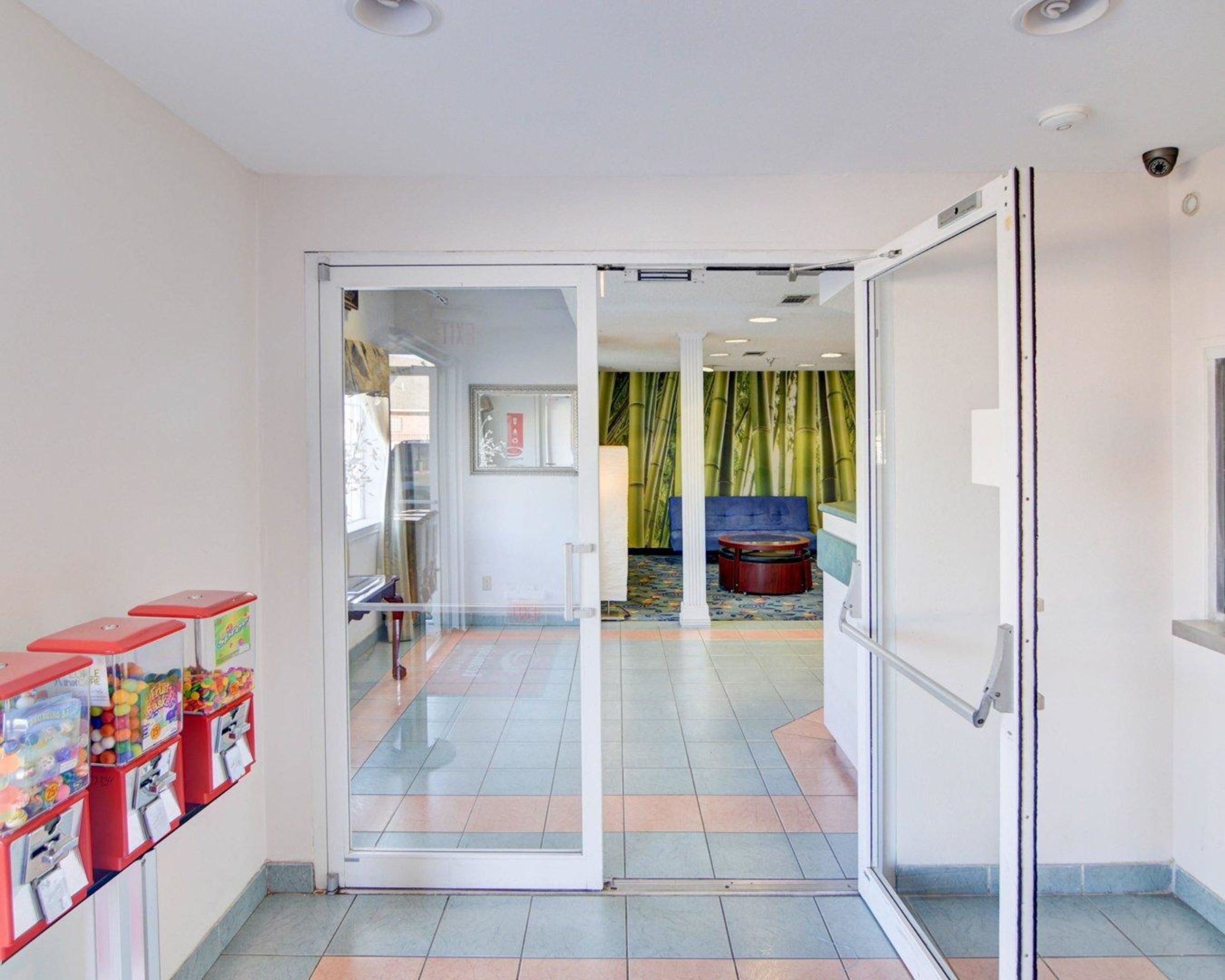 A hotel lobby with a glass door leading to a seating area with a blue sofa and a green curtain backdrop.