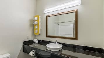 Un baño con lavamanos, espejo, toallero y retrete.