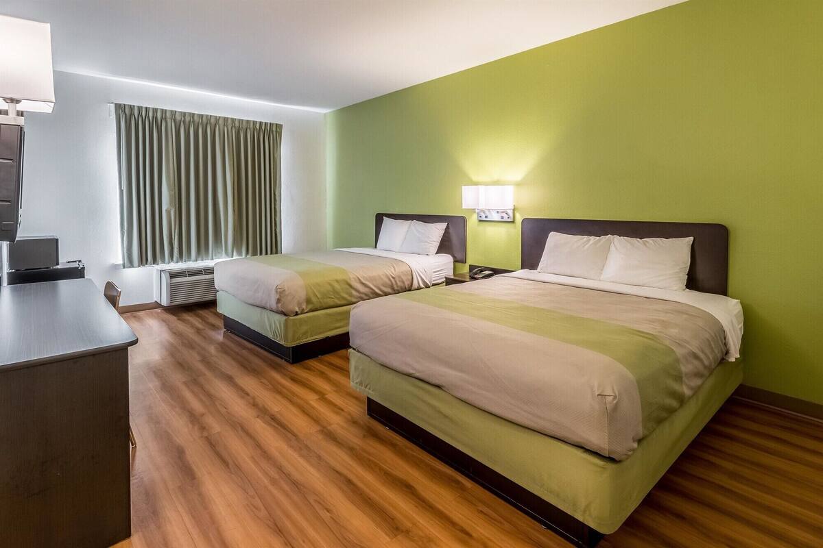 Une chambre d’hôtel avec deux lits, un bureau et une lampe.
