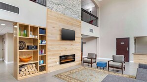 Amplia sala de estar con chimenea, un televisor de pantalla plana en la pared y un tapete grande.