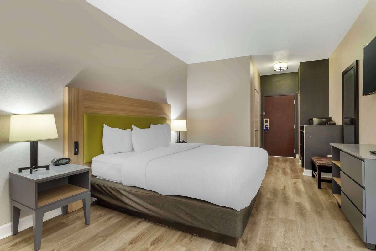 Une chambre d’hôtel comprenant un lit, des tables de chevet, un bureau, une chaise et une armoire.