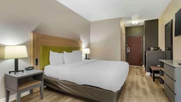 A hotel room with a bed, bedside tables, a desk, a chair, and a wardrobe.