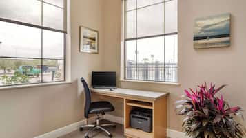 A room with a desk, chair, printer, and a potted plant.
