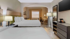 Una habitación de hotel con dos camas, un escritorio, una silla, un televisor y un aparador.