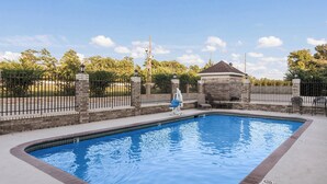 A rectangular swimming pool with a stone border, a gazebo, and a fence with a lamp post. - Red Roof Inn Conroe North - Willis (Willis)
