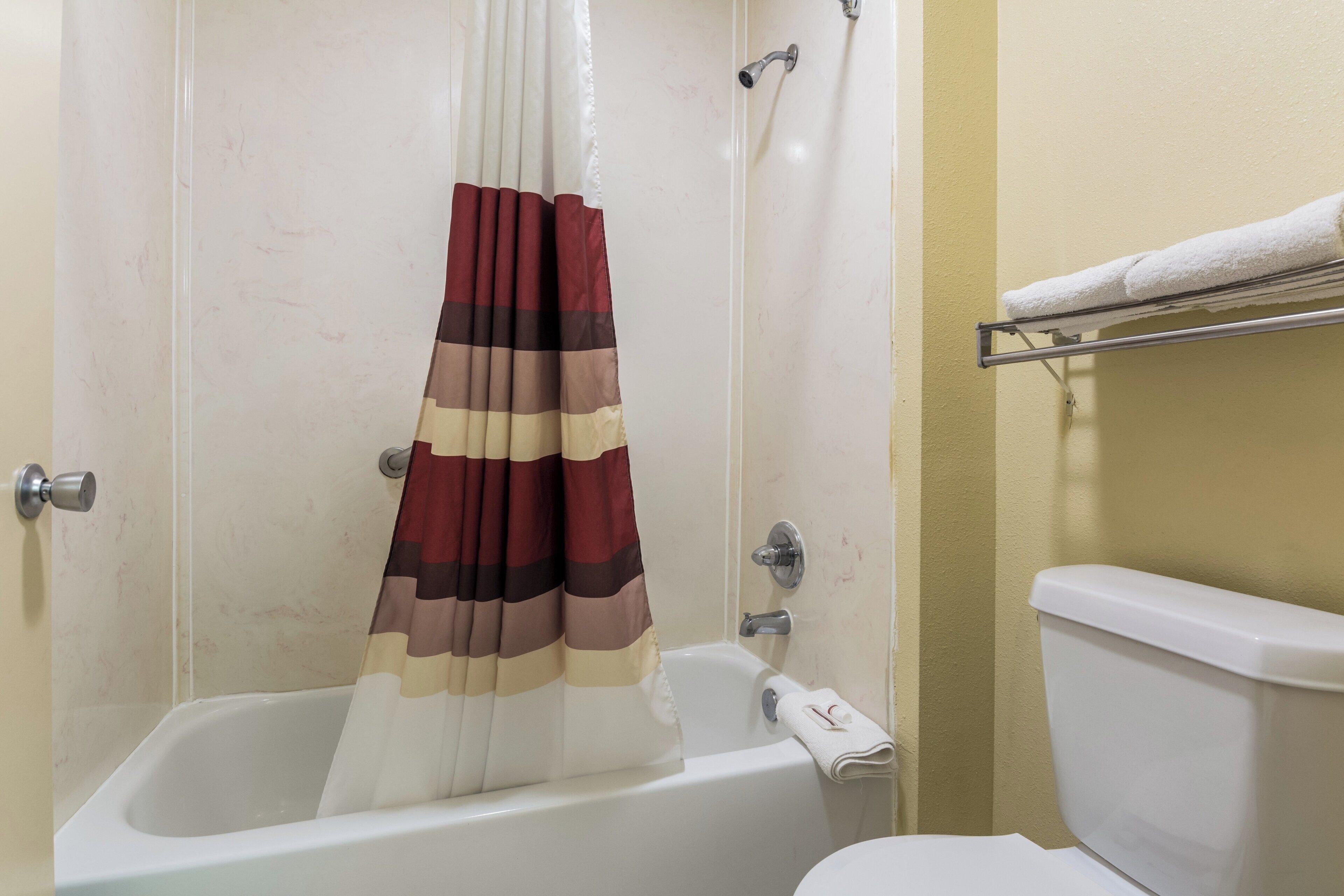 A bathroom with a bathtub, a toilet, and a shower curtain.