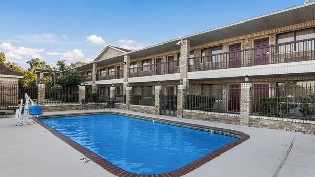 Un hotel con piscina, varios balcones y fachada de ladrillo.