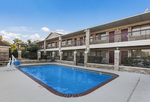 A hotel with a swimming pool, multiple balconies, and a brick facade. - Red Roof Inn Conroe North - Willis (Willis)