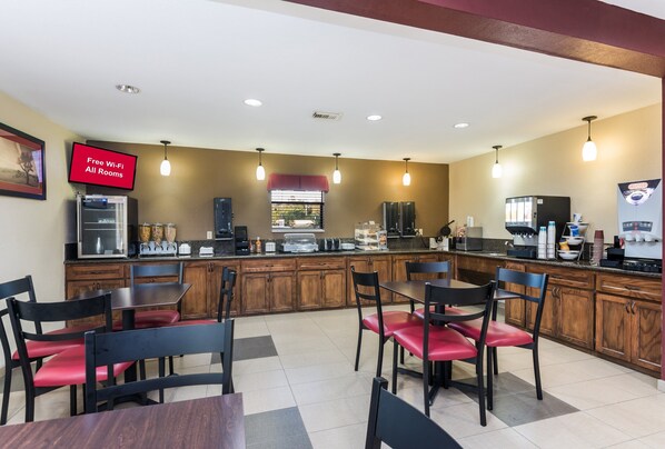 A modern kitchen with a central island, wooden cabinets, and a red sign indicating free Wi-Fi. - Red Roof Inn Conroe North - Willis (Willis)