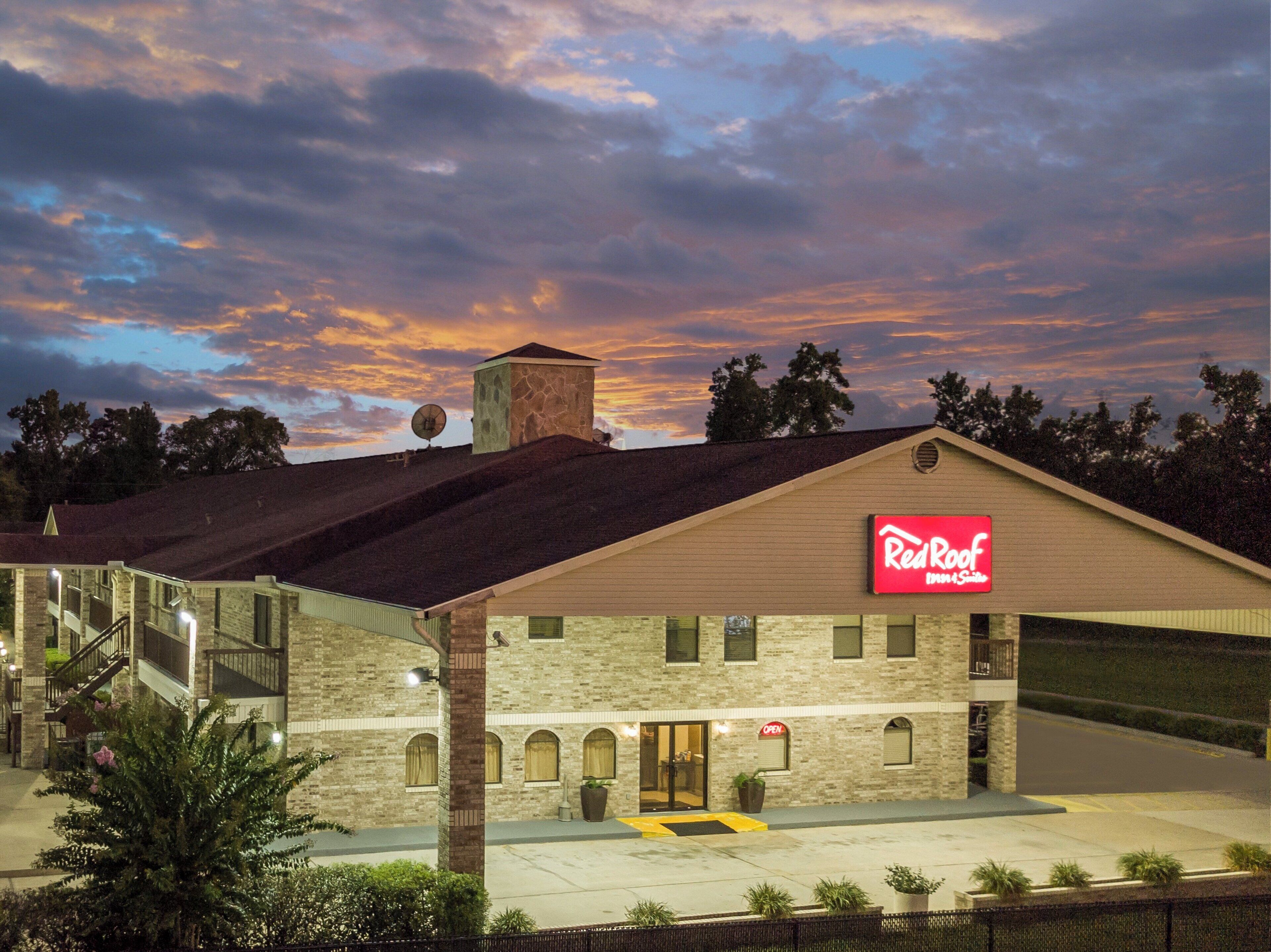 A Red Roof Inn with a brick facade, a large garage, and a clear sky with clouds.