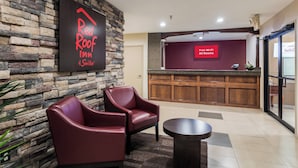 A reception area with a stone wall, a Red Roof Inn sign, a seating area with two chairs, a reception desk, and a digital screen advertising free Wi-Fi. - Red Roof Inn Conroe North - Willis (Willis)