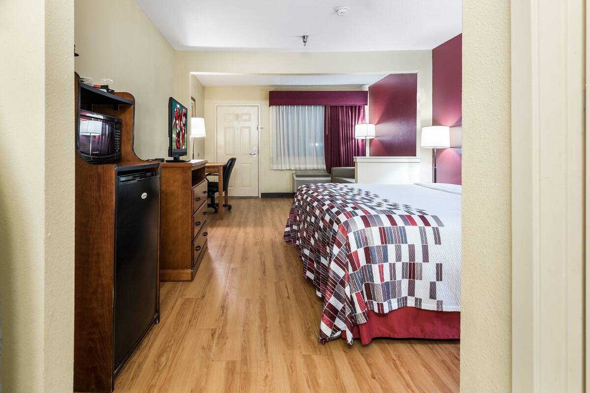 A hotel room with a bed, desk, chair, and a microwave.