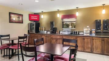 A restaurant with a counter, chairs, and tables.